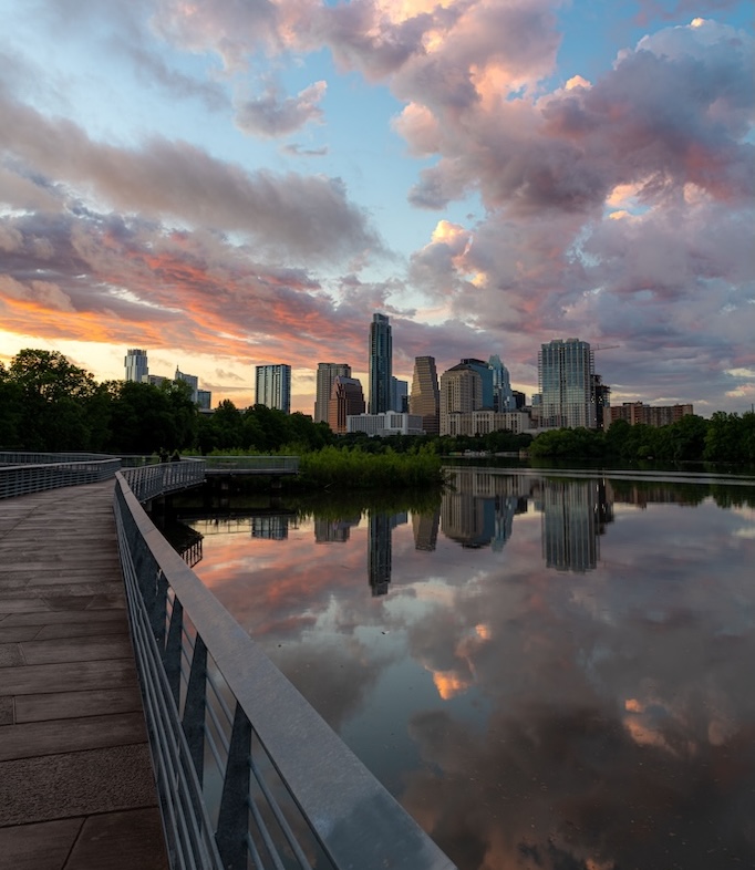 A vertical shot of TX skyline at sunset from the boardwalk along Town Lake in Austin city