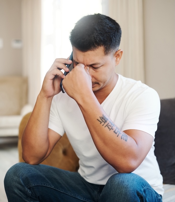 Man with his head in his hands on the phone.