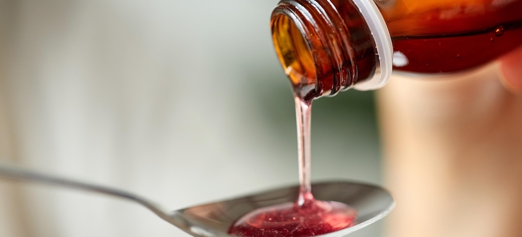 Close up of cough medicine being poured onto a spoon.